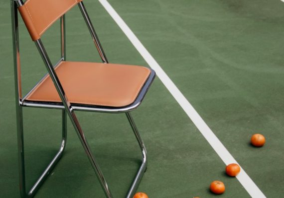 brown leather padded armless chair on tennis court